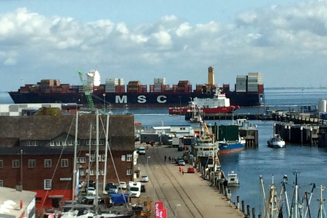 Aus dem Fenster der Reederei BREB in Cuxhaven sieht man große Containerschiffe vorbeifahren.