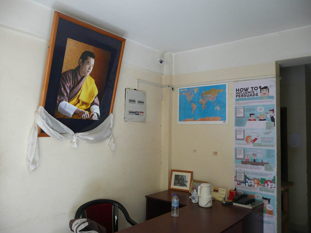 Ein Bild des Königs von Bhutan in einem Vorraum einer Redaktion. Der Seidenschal am Rahmen gleicht dem Kadak, einem Schal, der im bhuddistischen Umfeld häufig zum Abschied – zum Beispiel vor einer Reise – verschenkt wird.